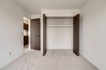 A walk in closet in a bedroom with white walls and carpet